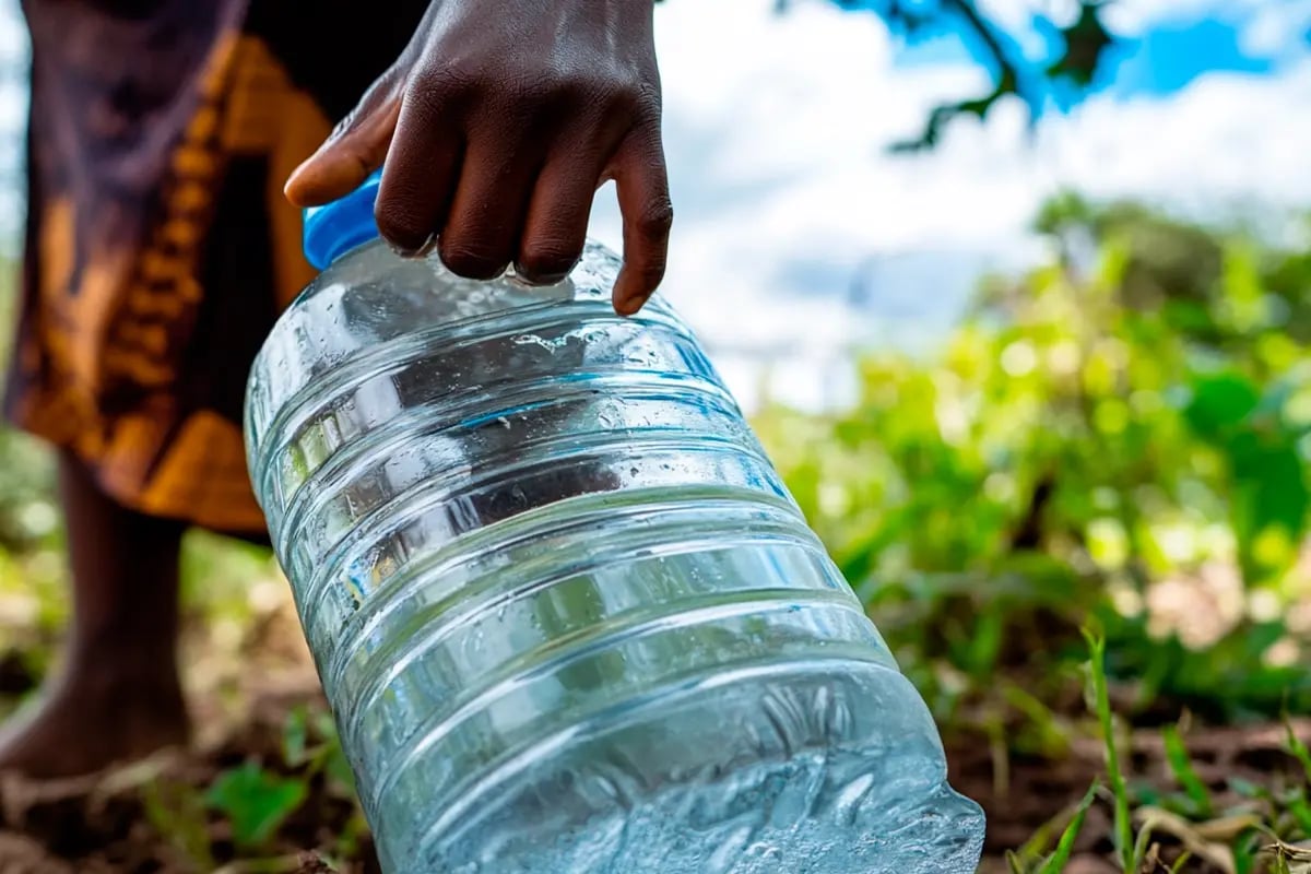 Sustainable impact of carbon credit investment_Close-up of a Tanzanian woman holding a bottle filled with clean water_visual 8